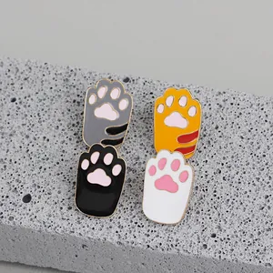 Cute cat paw enamel brooches in black, grey, orange, and white on a grey stone base