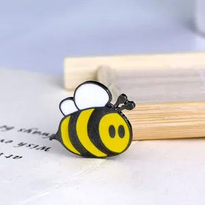 Cartoon enamel bee brooch in yellow and black on a book background for fashion styling