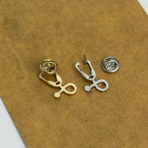 Vue détaillée de broches stéthoscope en or et argent avec texture métallique brossée