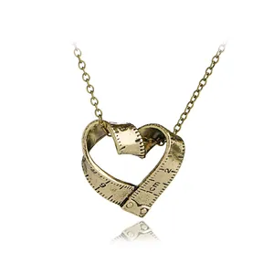 Détail d'un pendentif coeur en bronze vintage orné de marques de ruban à mesurer