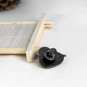 Detail of the black metal brooch back featuring a butterfly clutch and leaf-shaped design