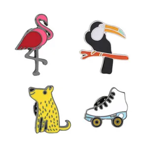 Close-up of four enamel pins including a flamingo, toucan, dog, and roller skates