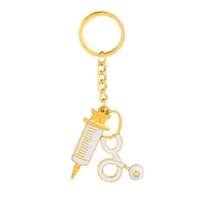 Detail view of medical keychain with golden syringe and stethoscope charms on white background