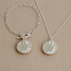 Close-up of tree of life pendant with glowing material and silver chain on textured base