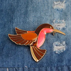 Spilla colibrì colorata in smalto su sfondo denim blu per donna