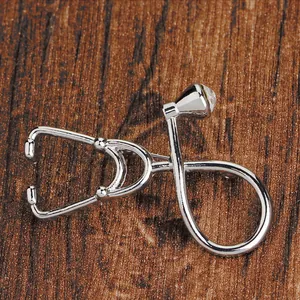 Detailed view of silver stethoscope brooch with sparkling rhinestone on dark wood surface