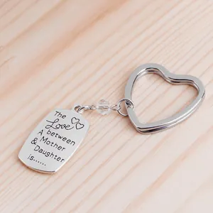 Polished silver heart keychain with Mother and Daughter engraved pendant on wood surface