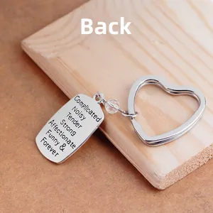 Polished heart keychain with engraved emotional text and clear bead on wood surface