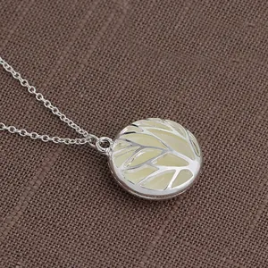 Close-up of circular tree of life pendant with glowing enamel inlay on rustic linen