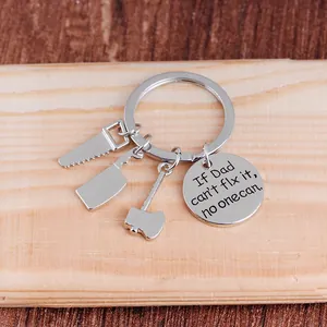 Close-up of tool-themed silver keychain charms with engraved Father's Day sentimental plaque