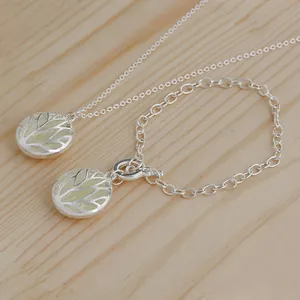 Detail of glow-in-the-dark Tree of Life necklace and bracelet set on a wooden surface
