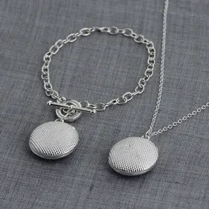 Detail of silver life tree necklace set with textured circular pendant and OT clasp