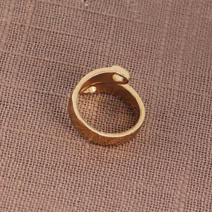 Macro detail of golden nail shaped ring with polished finish on textured background