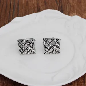 Square silver alloy cufflinks with geometric black enamel patterns and white rhinestones