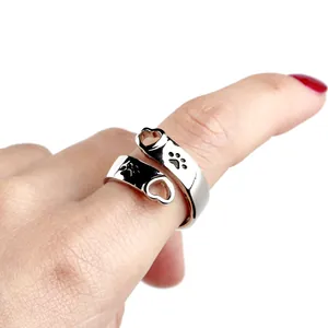 Macro detail of silver adjustable open ring with heart shapes and black paw prints