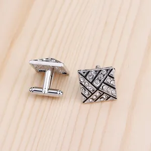Macro shot of silver alloy cufflinks with rhinestones and black enamel geometric patterns