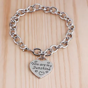 Détail macro du pendentif cœur en argent gravé You are my Sunshine sur chaîne en O