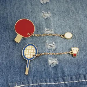 Creative badminton and table tennis enamel pins on blue denim fabric background
