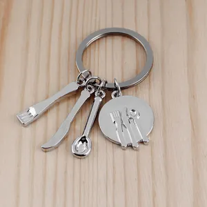 Polished silver keychain featuring fork, knife, spoon charms on light wood texture