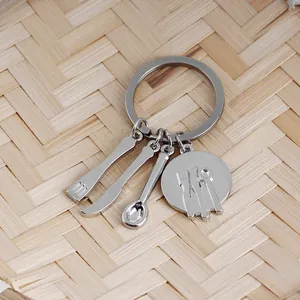 Detail of silver kitchen utensil charms on a keychain featuring mini fork, knife and spoon