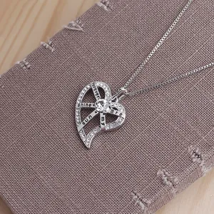 Gros plan du pendentif cœur argenté avec cristaux et gravure de soleil radieux