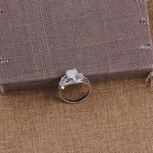 Detail of silver heart opal ring featuring intricate floral hollow carving and 4-prong setting
