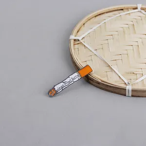 Detailed view of enamel cigarette pin with 'Never Knows Best' text on bamboo tray