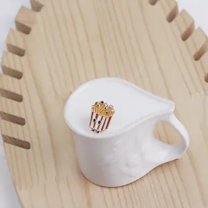 Detailed view of a cute cartoon french fries enamel pin on a white ceramic mug edge