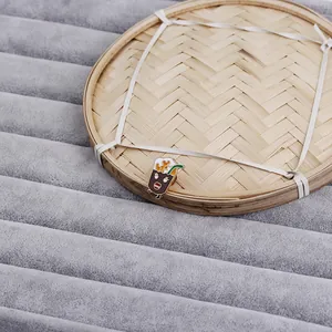 Detailed view of a cute cartoon beverage enamel pin on a textured velvet and bamboo tray