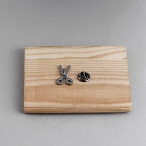 Detailed view of creative scissors brooch pin on wood texture with secure butterfly clasp