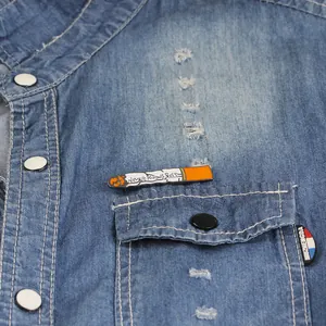 Creative cigarette enamel pin with Never Knows Best text on light blue denim shirt