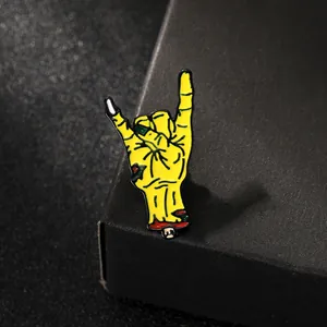 Macro shot of creative yellow zombie hand enamel pin with green nails and red bone detail