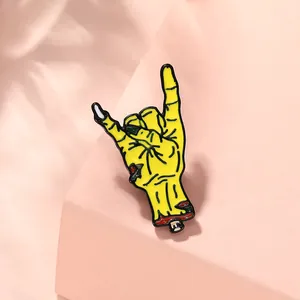 Close-up of yellow zombie hand enamel pin with rock gesture on pink geometric display