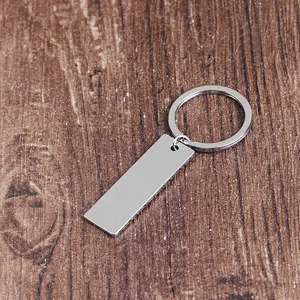 Close-up of rectangular silver stainless steel keychain pendant on dark wood surface