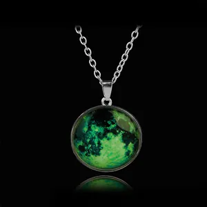 Luminous green moon pendant necklace with silver chain on black reflective surface