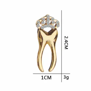 Golden tooth brooch with crown and rhinestones, size 2.4cm by 1.0cm on white background