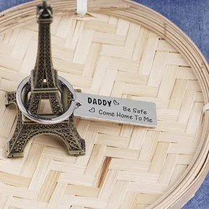 Close-up of daddy be safe metal keychain with Eiffel Tower charm on denim fabric background