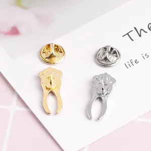 Golden and silver crown tooth brooches with rhinestone accents on a plaid background