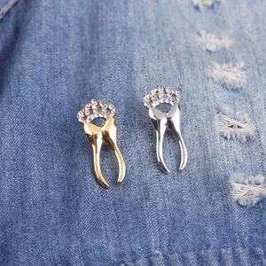 Golden and silver crown tooth brooches with sparkling crystals on blue denim fabric