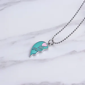 Detail of teal enamel half-heart pendant with pink accent and BE FRI engraving on bead chain