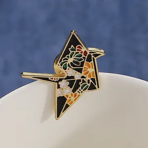 Vintage origami crane enamel brooch with floral patterns on a ceramic cup edge