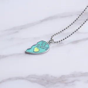 Close-up of heart-shaped friendship pendant with turquoise enamel and silver bead chain