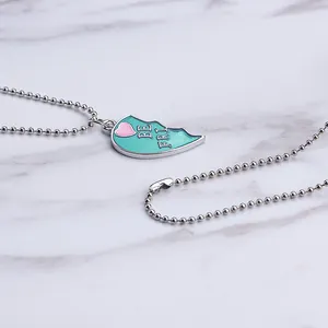 Macro detail of silver-toned half-heart Best Friends pendant with mint green enamel