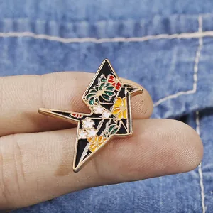 Macro detail of enamel origami crane brooch with floral pattern on denim background