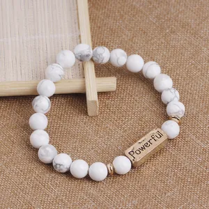 Macro view of white natural stone beaded bracelet with golden Powerful engraved plaque