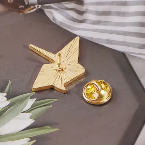 Detail of gold enamel origami crane brooch back with textured finish and butterfly clasp