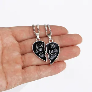 Detailed view of silver Big Sis and Little Sis heart necklaces with black enamel flowers