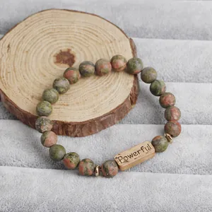 Detail of Unakite stone beaded bracelet featuring a gold Powerful engraved metal plate