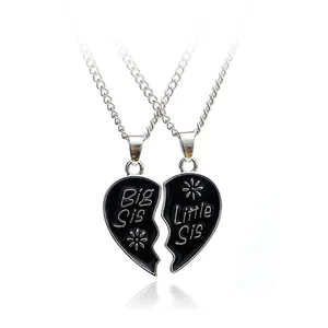 Close-up of split heart puzzle pendants engraved with Big Sis and Little Sis text