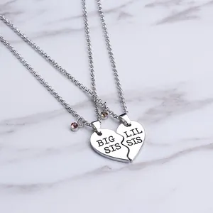 Big Sis and Lil Sis heart split pendant necklaces on marble background with crystals